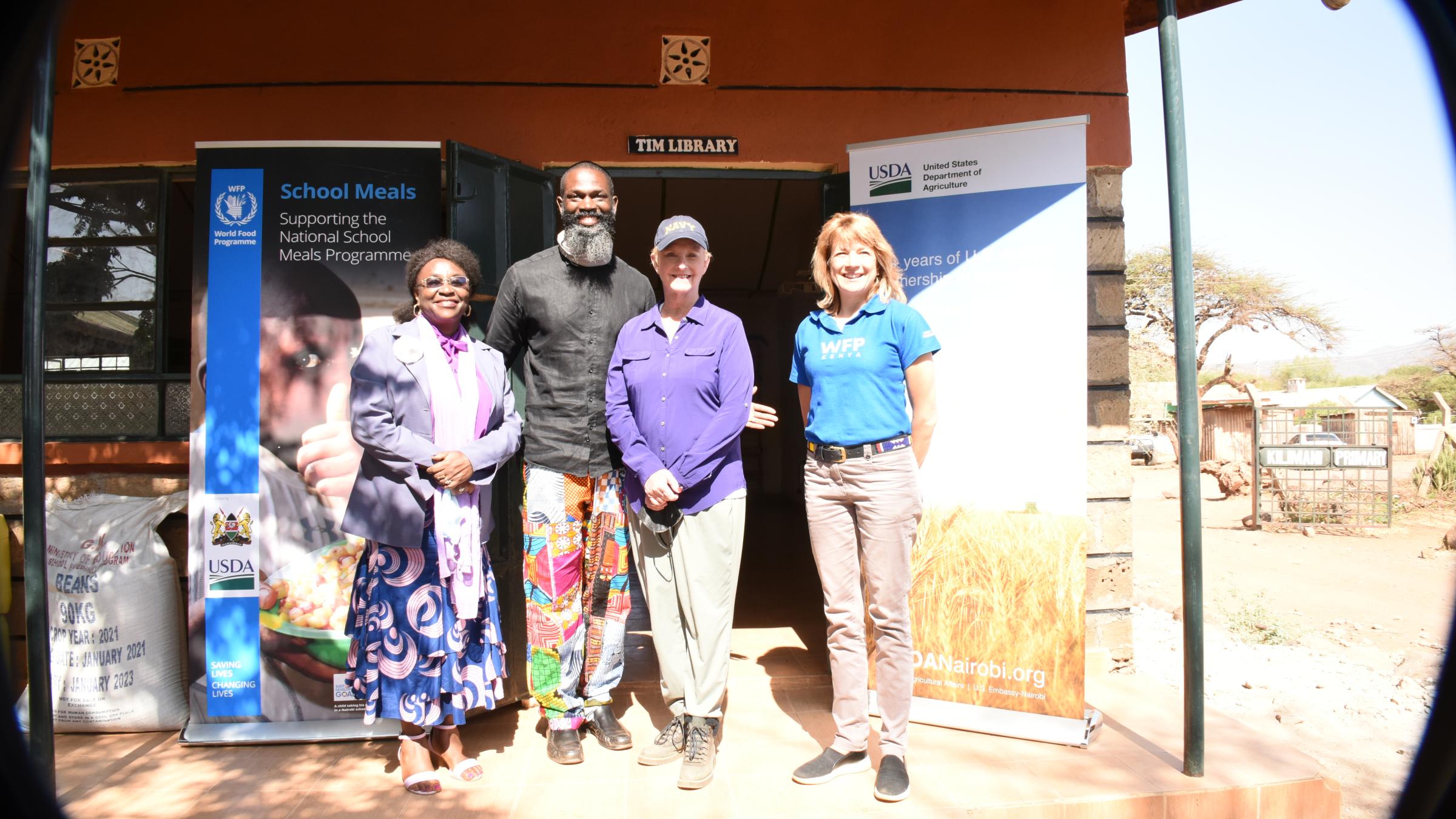 Four individual standing in front of school in Kenya