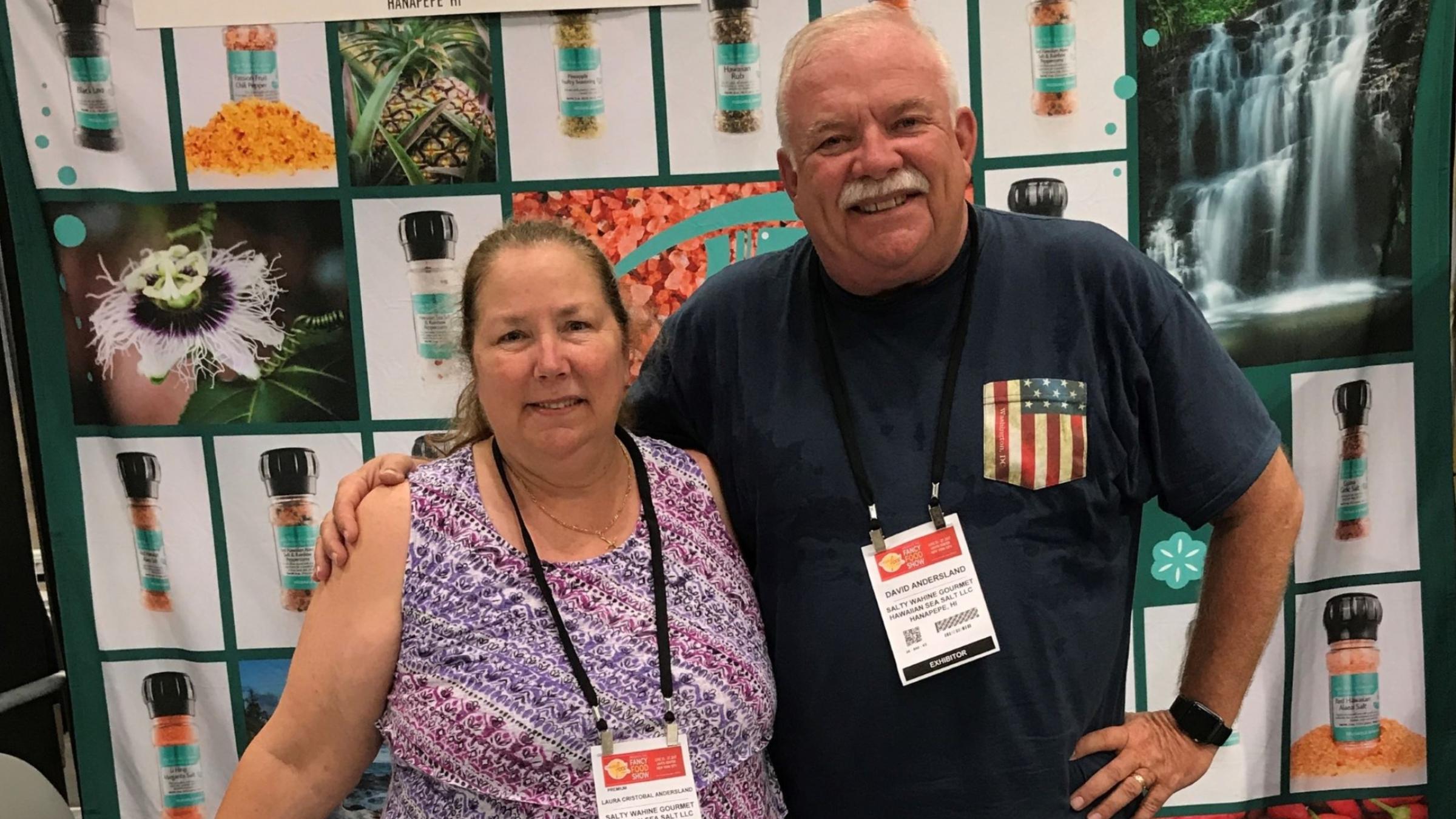 Husband and wife, veteran- and woman-business owners David and Laura Andersland pose behind a table of spices at a trade show.