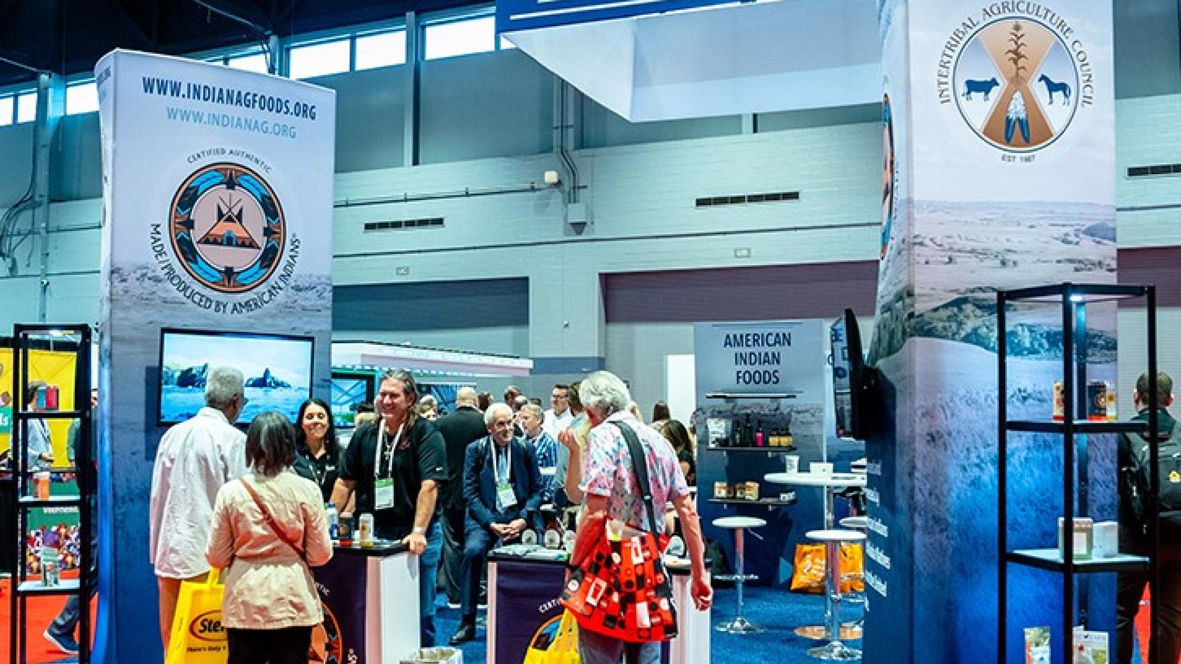 A booth that is promoting "American Indian Foods" attracts a number of spectators who are talking to the agribusiness owners.