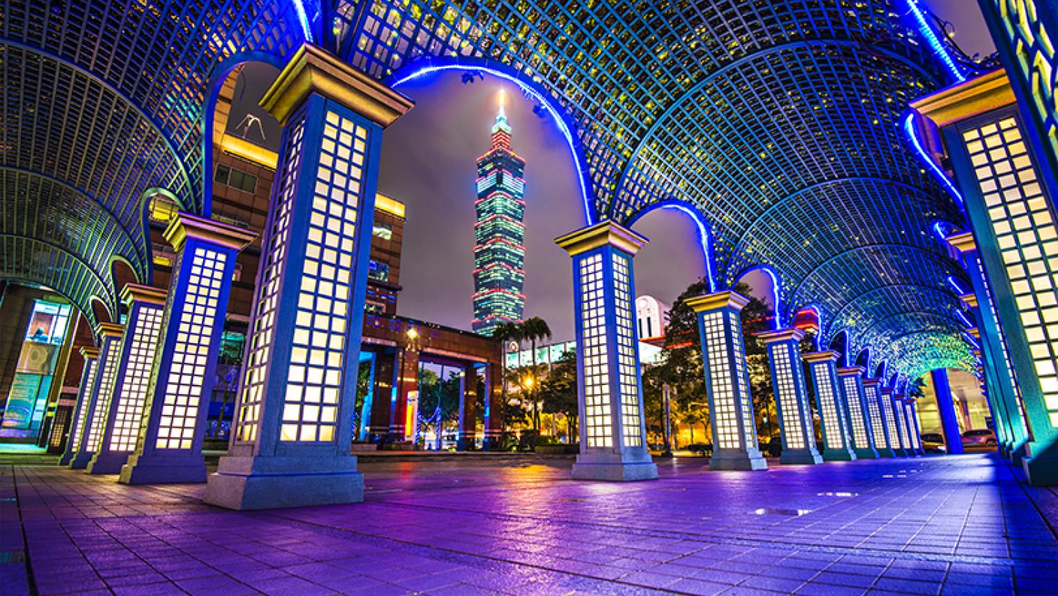 Nightime cityscape through building arches in Taipei